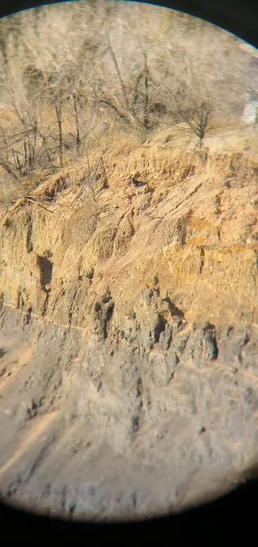 a man looks through binoculars at a cliff