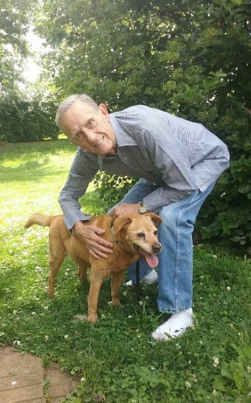 an elderly gentleman with his brown dog in the park