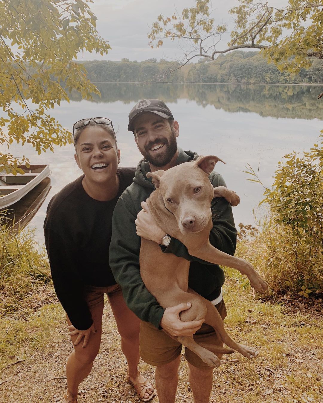 couple holding a pit bull at the lake