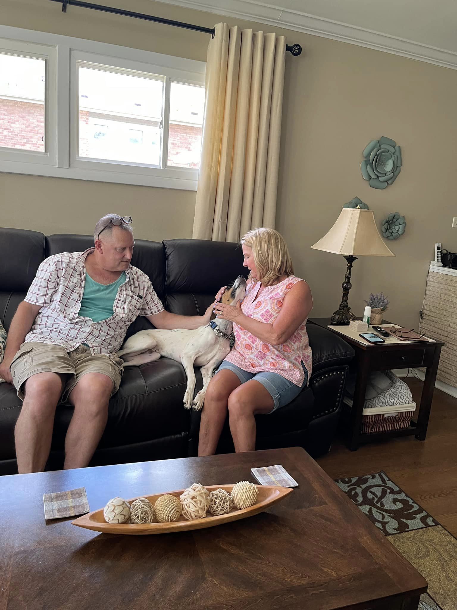 man and woman petting the dog on couch