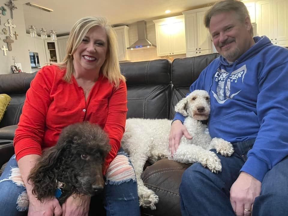 man and woman sitting on couch with two dogs