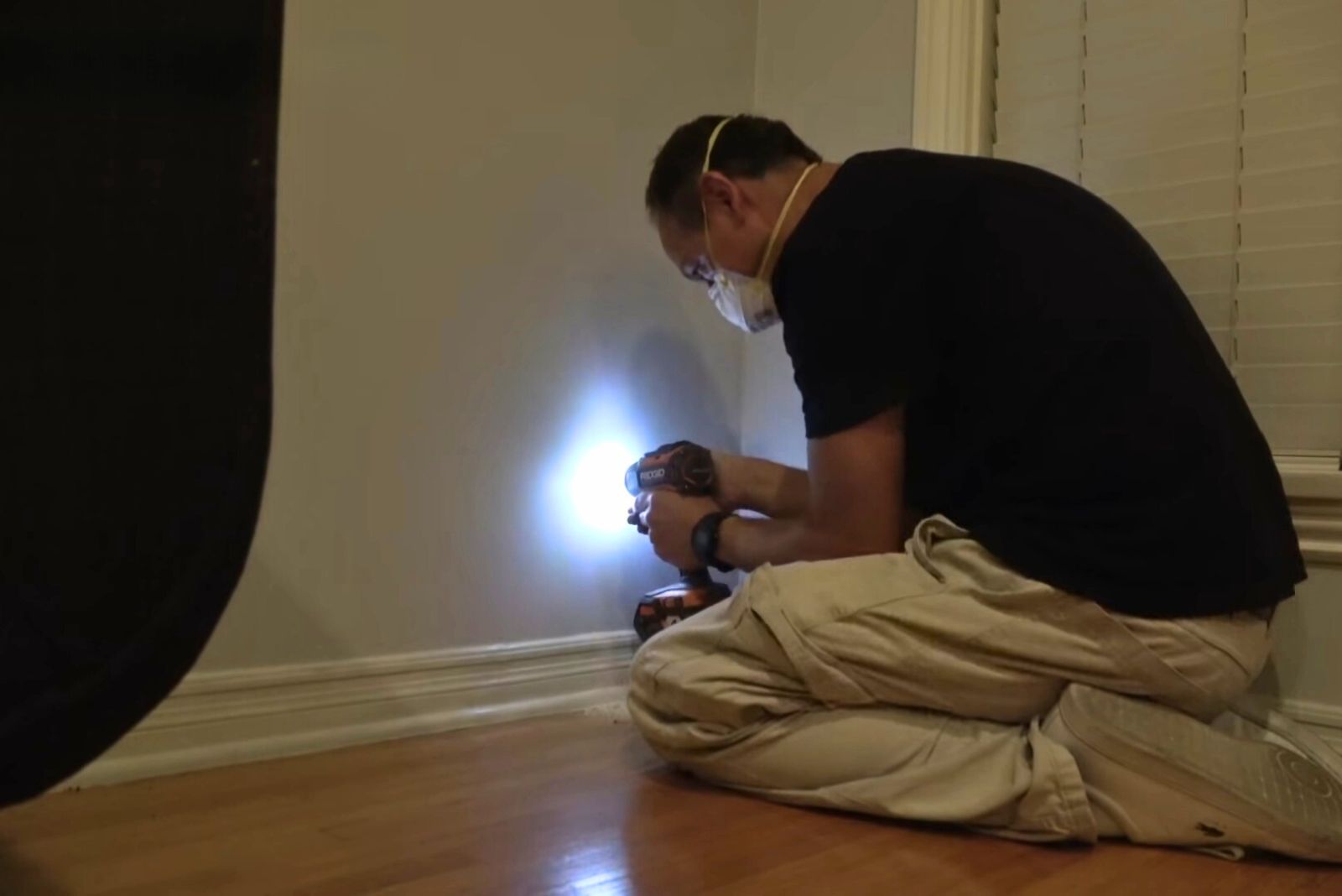 man with face mask trying to make a hole in the wall