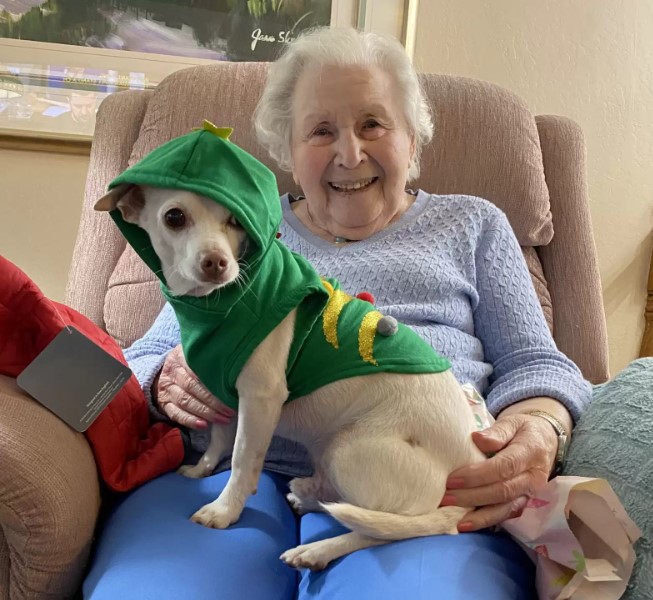 older woman sitting in chair with dog in her lap