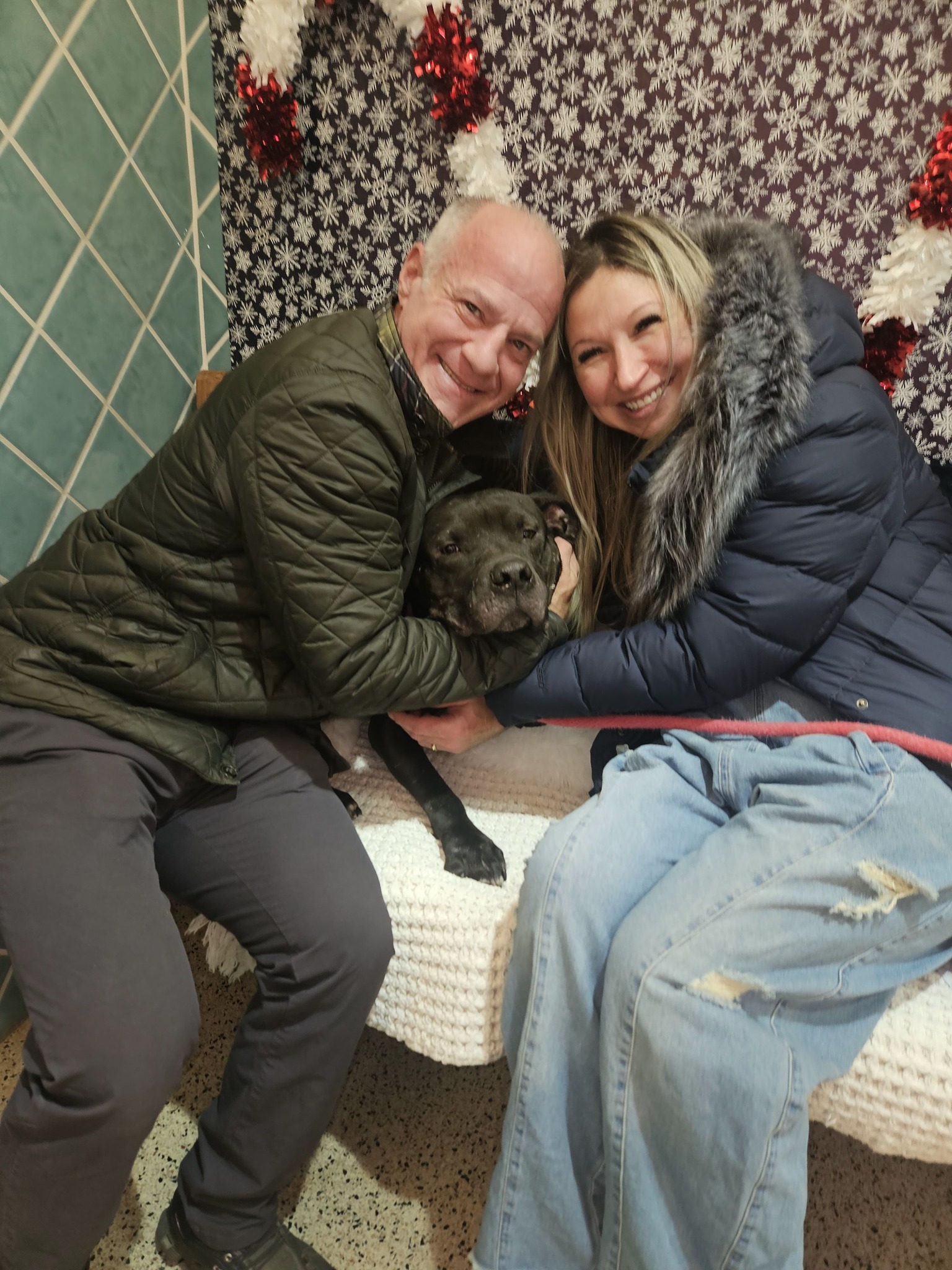 smiling man and woman hugging black dog