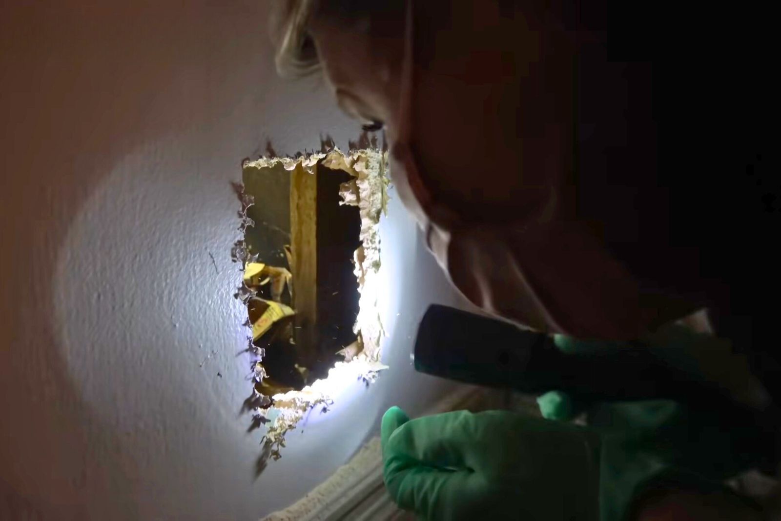 woman looking through the wall hole