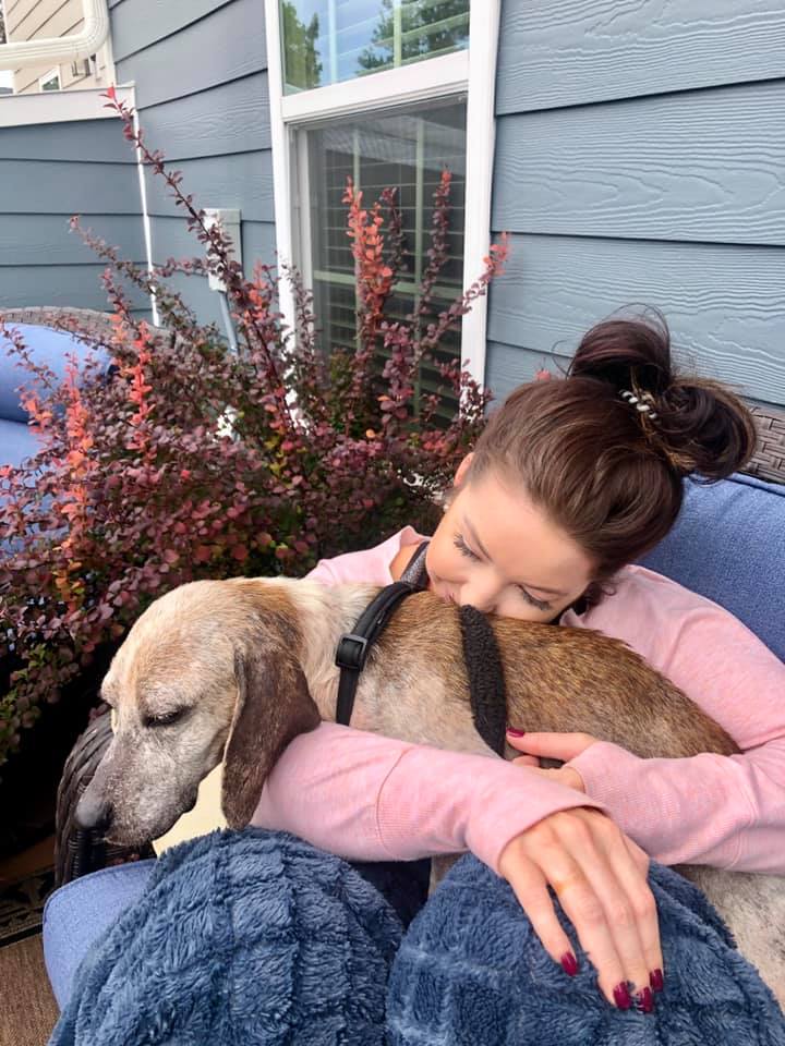 young woman cuddling with dog in her lap