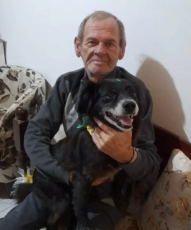 a black dog in the arms of an elderly man