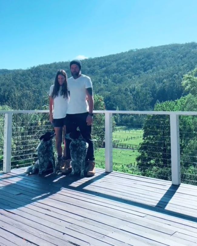 a man and a woman are standing on the terrace with two dogs