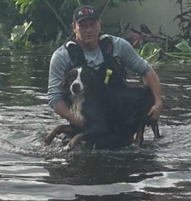 a man carries a dog in the water