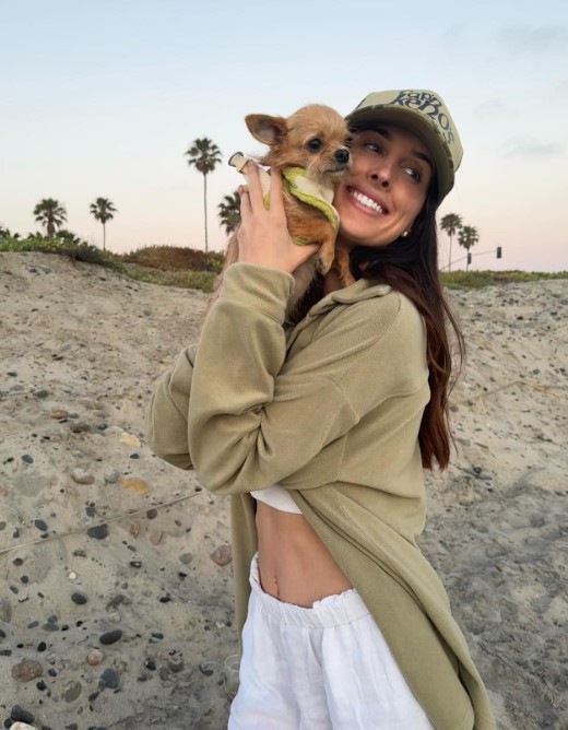 a smiling girl holds a dog in her arms