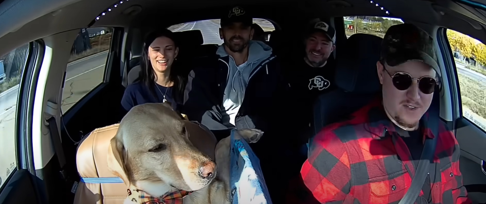 four people and dog in car