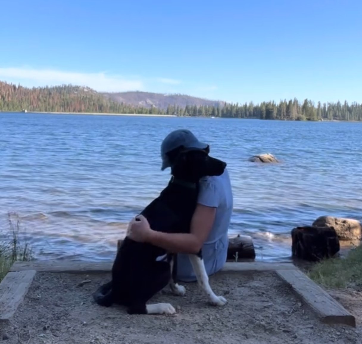 woman hugging his dog by the lake