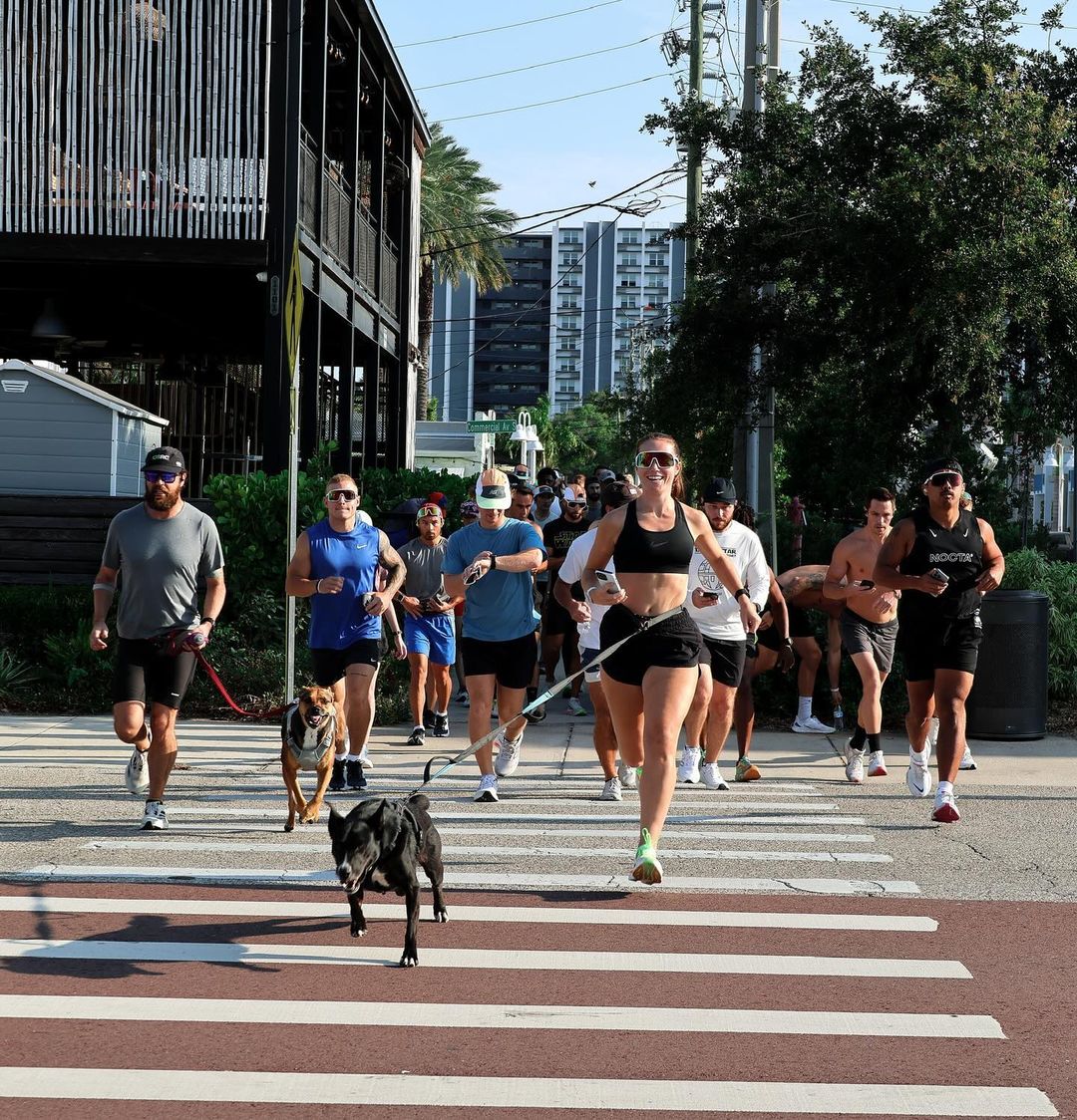 woman running with dog and other runners on the street