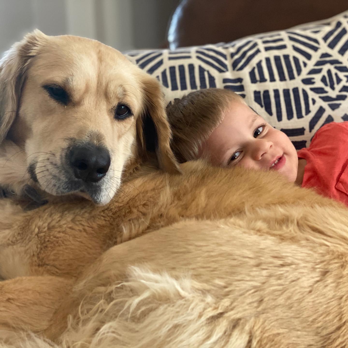 the boy is lying next to his dog