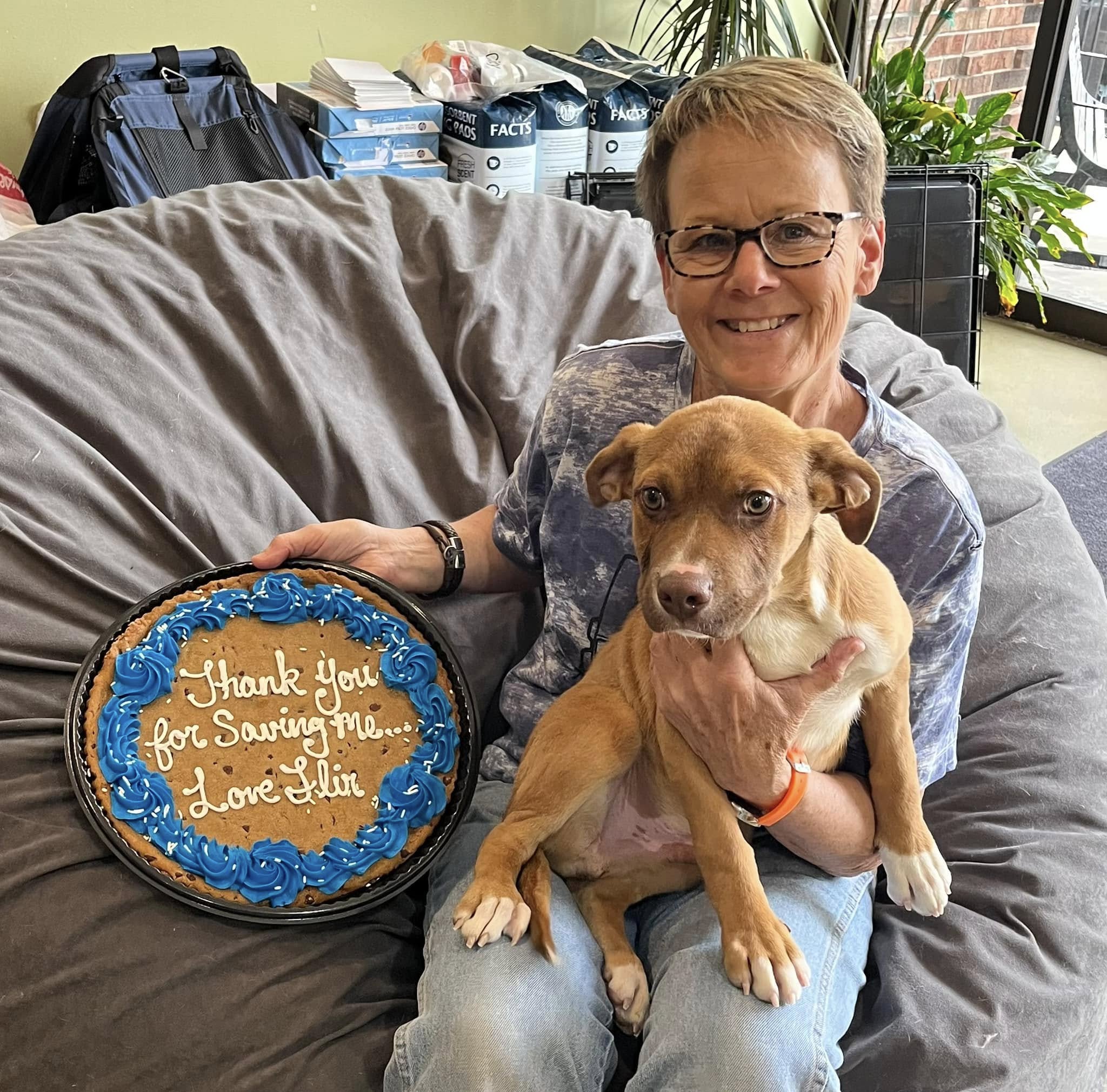 woman holding a cake and a pup